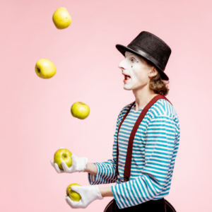 pink background, Mime juggling yellow apples in foreground